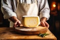 A farmer demonstrates a piece of cheese he made with his own hands. Homemade cheese production on a farm. Natural product. Close-