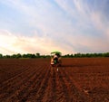 A farmer doing farming with his tractor in farm agriculture image. Red fields Royalty Free Stock Photo