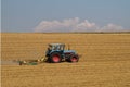 a blue tractor on a harvested grain field