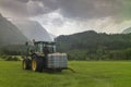 A farmer drives his tractor in a field while fertilizing his crops during a cloudy day