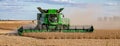 A farmer driving a combine harvester harvesting a soybean crop