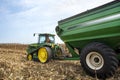 Farmer driving tractor and grain cart in farm corn field