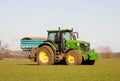 Farmer driving a tractor and sprinkling fertiliser on a field.