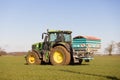 Farmer driving a tractor and sprinkling fertiliser on a field.