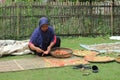 a farmer drying food in the form of crackers to dry in the hot sun