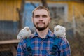 A farmer of European Caucasian a man with a beard portrait in a shirt with two dwarf white chickens on his shoulder, close-up Royalty Free Stock Photo