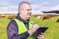 Farmer with folder near the cows at pasture