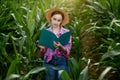 Farmer with a folder stands in a corn field and checks the growth of vegetables. Agriculture - food production, harvest concept