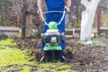 A farmer in the garden tills the land with a motorized cultivator or power tiller, preparing the soil for planting crops Royalty Free Stock Photo