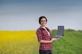 Farmer girl with laptop in rapeseed Royalty Free Stock Photo