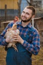 Farmer handsome smiling european caucasian rural portrait in countryside with beard, shirt and overalls looks at camera with