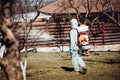 Hard working handyman wearing protective clothing using backpack machine for spraying organic pesticides