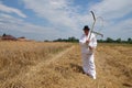 Farmer harvesting wheat with scythe Royalty Free Stock Photo