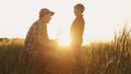 Farmer and his son in front of a sunset agricultural landscape. Man and a boy in a countryside field. Fatherhood Royalty Free Stock Photo