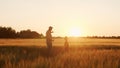 Farmer and his son in front of a sunset agricultural landscape. Man and a boy in a countryside field. Fatherhood Royalty Free Stock Photo