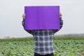 Farmer hold blank violet paper poster at garden background Royalty Free Stock Photo