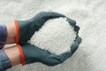 Farmer holding ammonium nitrate pellets in hands over pile, top view. Mineral fertilizer