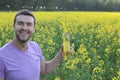 Farmer holding colza oil bottle with yellow flowers in the background Royalty Free Stock Photo
