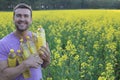 Farmer holding colza oil bottle with yellow flowers in the background Royalty Free Stock Photo