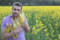 Farmer holding colza oil bottle with yellow flowers in the background Royalty Free Stock Photo