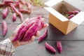 Farmer holding fresh sweet potatoes with blur paper box on wooden background. Royalty Free Stock Photo