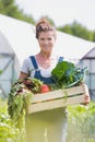 Farmer holding organic produce in wooden box on her farm