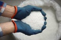 Farmer holding pile of ammonium nitrate pellets over bag, top view. Mineral fertilizer