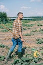 farmer holding rake and watering can while walking