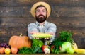 Farmer with homegrown harvest. Farmer rustic villager appearance. Grow organic crops. Farmer straw hat presenting fresh Royalty Free Stock Photo