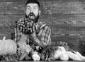Farmer with homegrown harvest on table. Farmer proud of harvest vegetables and grapes. Man bearded holds grapes wooden