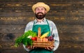 Farmer with homegrown vegetables in basket. Man bearded farmer presenting eco vegetables wooden background. Fresh Royalty Free Stock Photo