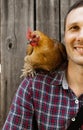 The farmer hugs a chicken. pleasant man is hugging a cock. close up shot emotions.