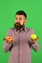 Farmer with indecisive face holds fresh fruit.