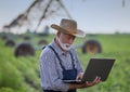 Farmer with laptop in front of irrigation system in field