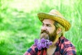 Farmer with lilac flower in beard. Ecology. Green field in summer. Countryman on green meadow. protect green environment