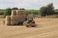 Round hay bales in a field in the British countryside being harvested by tractor on to a truck Wakefiel, West Yorkshire UK Royalty Free Stock Photo