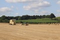 Round hay bales in a field in the British countryside being harvested by tractor on to a truck Wakefiel, West Yorkshire UK Royalty Free Stock Photo