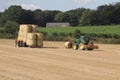 Round hay bales in a field in the British countryside being harvested by tractor on to a truck Wakefield, West Yorkshire UK Royalty Free Stock Photo