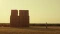 Farmer looking haystack field at golden sunset. Modern agribusiness industry