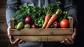 Farmer man holding wooden box full of fresh raw vegetables in his hands. Basket with vegetable in the hands. Generative AI Royalty Free Stock Photo