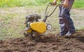 Farmer man plows the land with a cultivator. Agricultural machinery for tillage in the garden