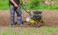 Farmer man plows the land with a cultivator. Agricultural machinery for tillage in the garden