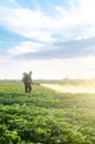 A farmer with a mist sprayer blower processes the potato plantation from pests and fungus infection. Fumigator fogger. Use Royalty Free Stock Photo