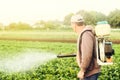 A farmer with a mist sprayer spray treats the potato plantation from pests and fungus infection. Agriculture and agribusiness. Royalty Free Stock Photo
