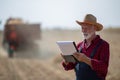 Farmer with notebook in field during harvest Royalty Free Stock Photo