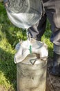 Farmer passes the milk through the strainer, the old way of cleaning milk from dirt