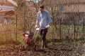 Farmer performing garden soil tillage with old poor cultivator tiller agricultural machine