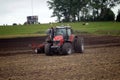 Farmer plowing the field Cultivating tractor in the field Red farm tractor with a plow in a farm field Tractor and Plow. Lithuania