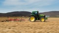 A farmer plowing with a John Deere tractor. Sunny day on the field. It`s a panning shot, that cause the blurry background and for