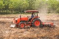 Farmer plowing stubble field with orange tractor Royalty Free Stock Photo